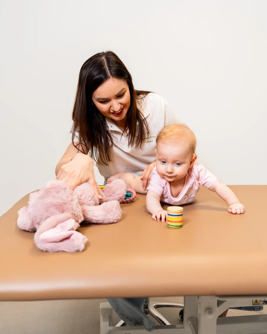 Fizjoterapeutka BeHealthy Dla Dzieci podczas zabawy z niemowlęciem na stole terapeutycznym